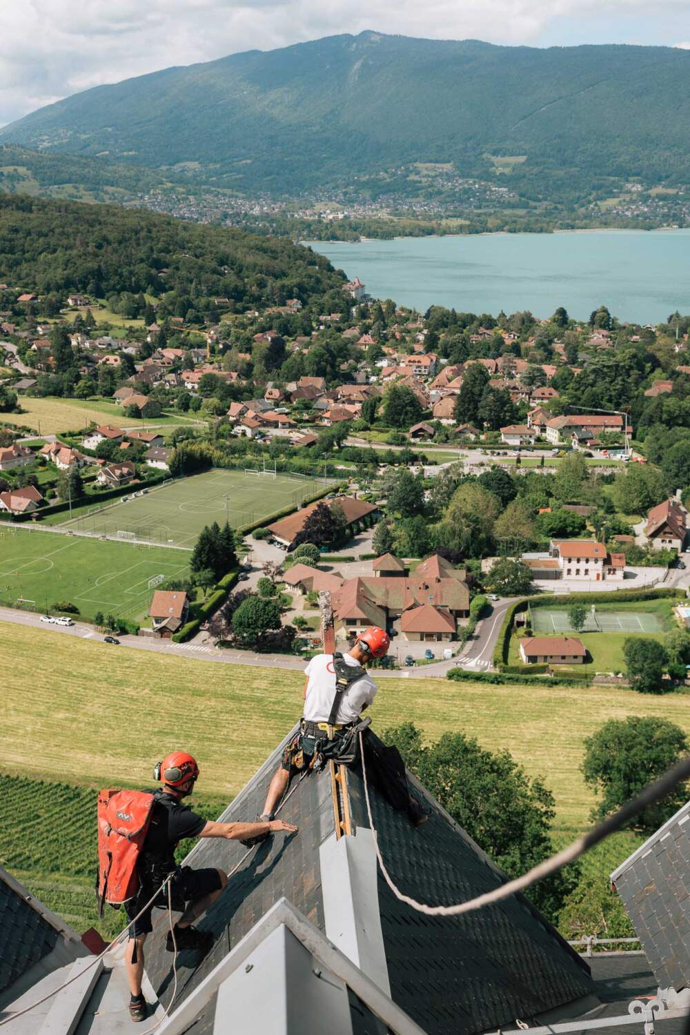 Vue d'un salarié à cheval sur le toit du château de Menthon avec le lac d'Annecy en face